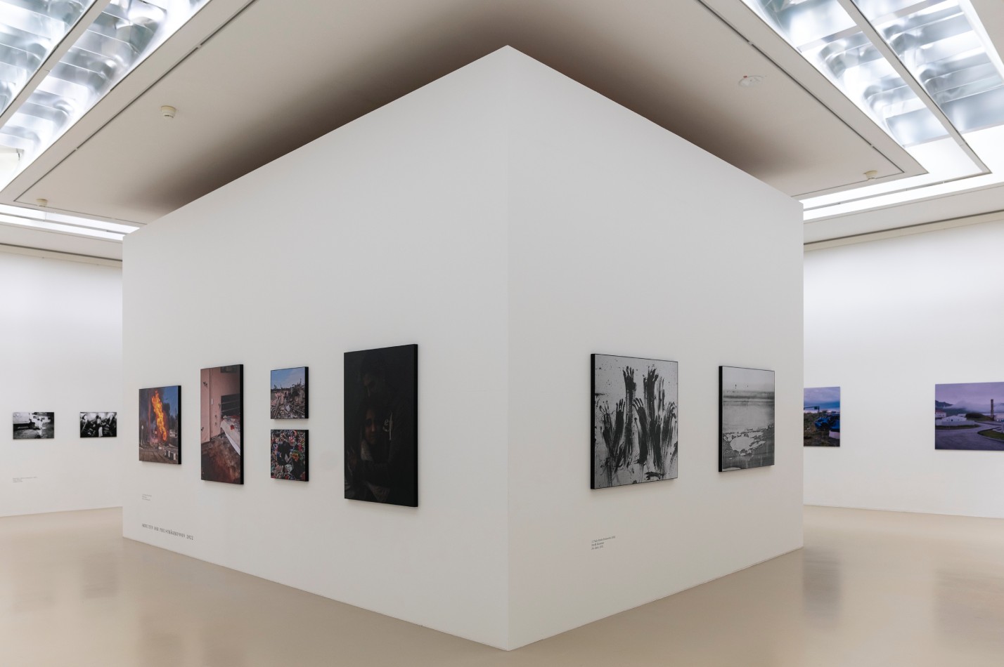 Ausstellung Sprengel Museum Hannover Galerieraum mit einer Art Würfel in der Mitte. An den weißen Wänden hängen verschiedene Fotografien.
