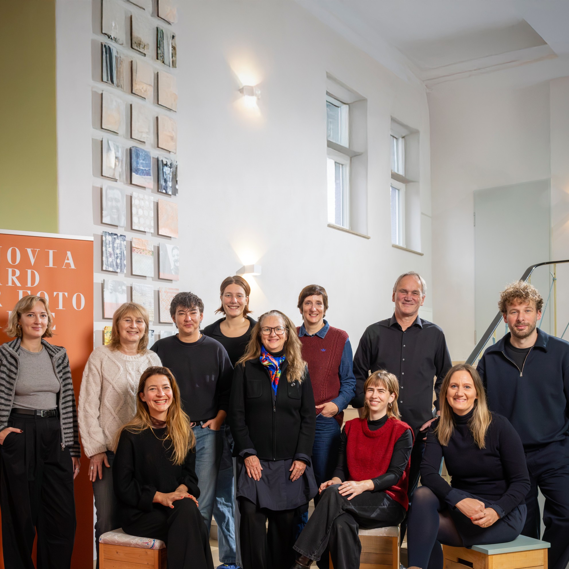 Eine Gruppe von 11 Personen steht und sitzt in einem Innenraum vor einem Banner für den Vonovia Award für Fotografie.